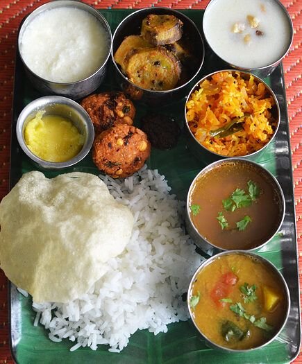 A traditional South Indian special veg meals served on a banana leaf with rice, curries, and side dishes.