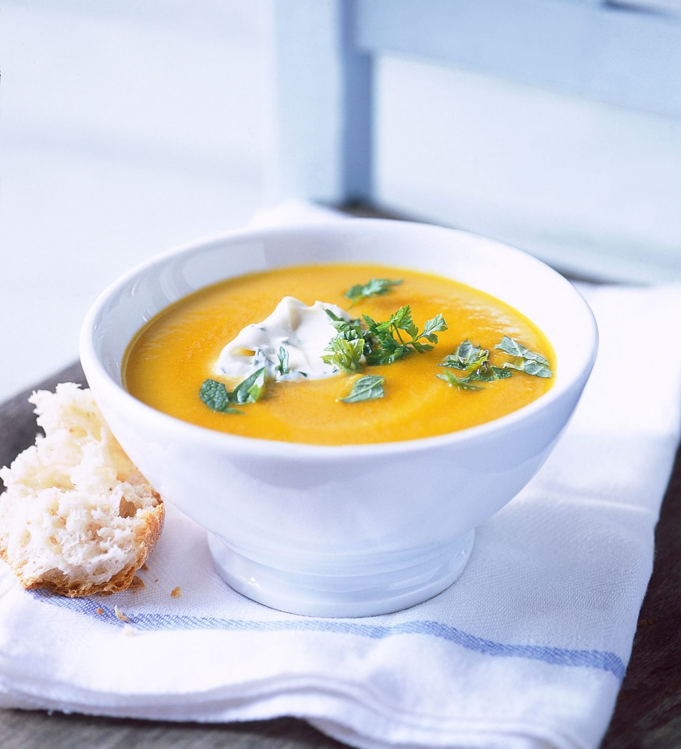 A bowl of hot vegetable soup served steaming with herbs and vegetables.