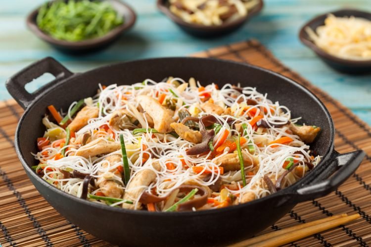 A plate of fried rice and noodles served hot with vegetables and sauce