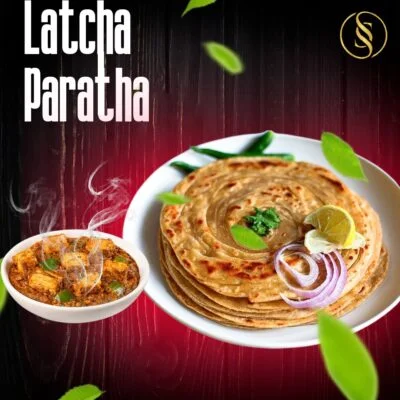 A stack of crispy layered latcha parathas served on a plate with butter.